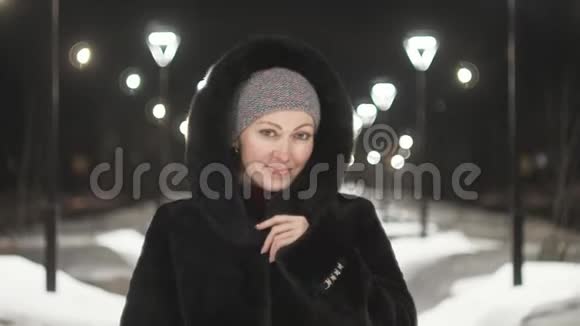 穿着黑色皮衣走着的漂亮女人户外活动女孩在冬天的夜晚漫步在城市的路灯之间视频的预览图