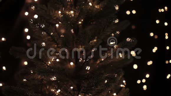 女人在圣诞树上装饰金色圣诞球背景是bokeh灯视频的预览图