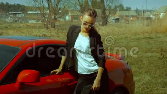 一位红唇在跑车附近摆姿势的商务女士视频的预览图