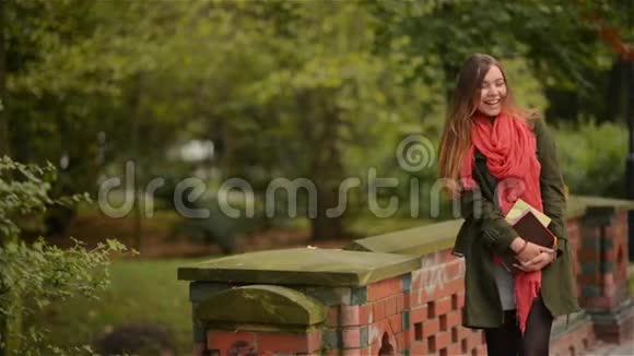 学生女孩拿着书穿着背包户外微笑快乐地在公园里散步高加索女子大学或视频的预览图