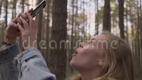 女孩在智能手机摄像头拍摄森林照片视频的预览图