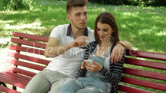 在手机里看他女朋友在长凳上的照片的人视频的预览图
