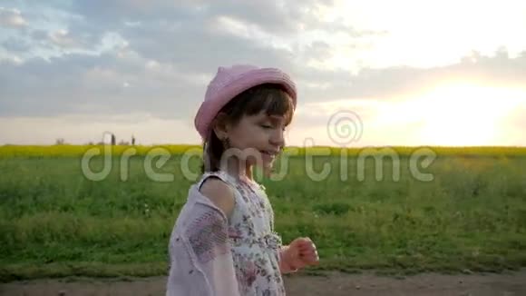 在背光中奔跑的女孩子肖像微笑的女孩沿着田野的道路奔跑快乐的孩子在城外玩视频的预览图