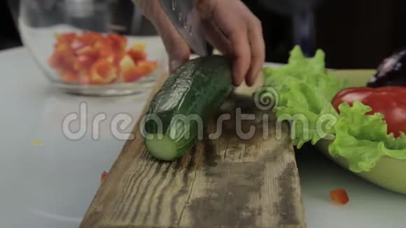 女人在厨房桌子上切黄瓜做沙拉在木质砧板上切菜视频的预览图