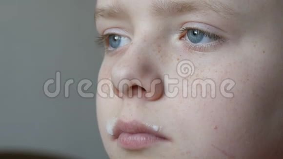 一个有着蓝眼睛和雀斑的小男孩他从一个带有奶胡子的玻璃烧杯里喝牛奶视频的预览图