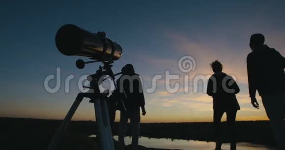 暮色中的朋友透过望远镜看视频的预览图