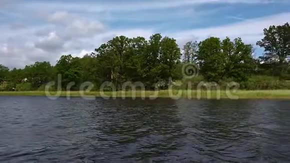 湖岸绿树上美丽的景色深蓝色的水面和绿色的树木蓝天上有白云的背景视频的预览图