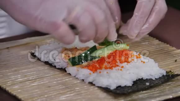 特写厨师用黄瓜和鱼子酱做寿司卷视频的预览图