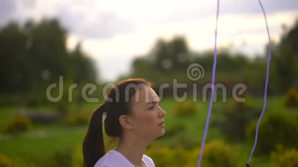 年轻女子在摩天轮的背景下在公园里跳绳视频的预览图
