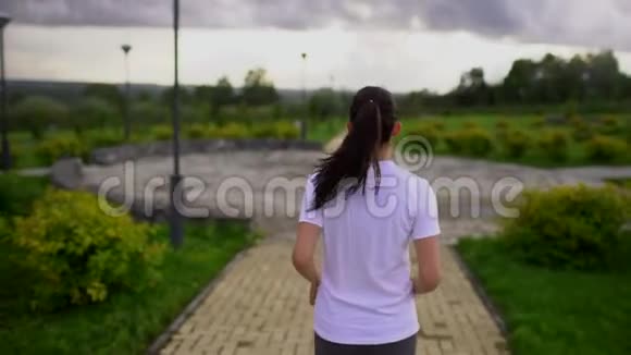 年轻漂亮的女人在公园里跑步从后面拿走的慢动作视频的预览图