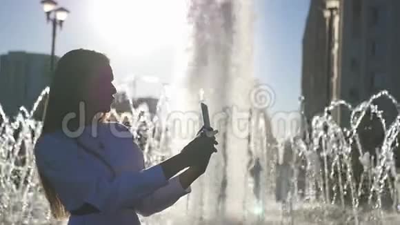 一个漂亮的女孩在喷泉处自拍在相机上接吻高清1920x1080慢动作视频的预览图