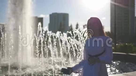 一个漂亮的女孩站在一个夏天的喷泉附近自拍高清1920x1080慢动作视频的预览图
