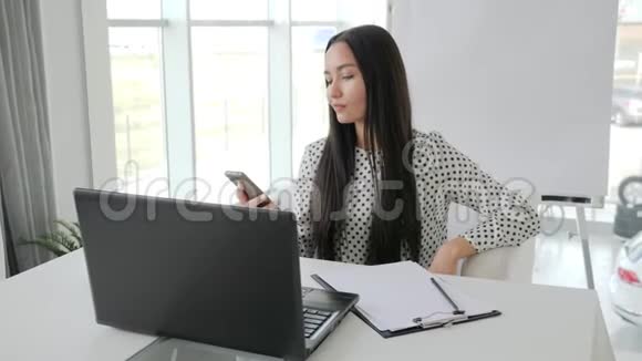 员工在手机上讲话漂亮的秘书在白色办公室打电话女经理在笔记本电脑上打印文本视频的预览图