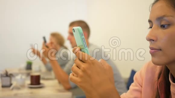 美丽的混合种族女孩使用手机和微笑在咖啡馆免费的年轻人使用小工具高清视频的预览图