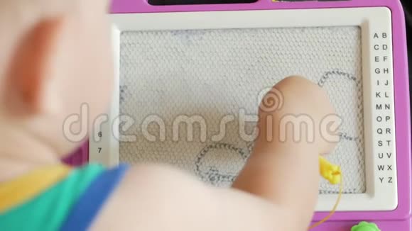 一个2岁的好男孩在一个磁性画板上画画他有许多难以理解的人物孩子很努力视频的预览图