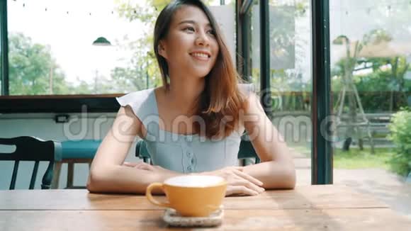 活泼开朗的亚洲年轻女人在咖啡馆里喝着热咖啡或茶享受着它视频的预览图