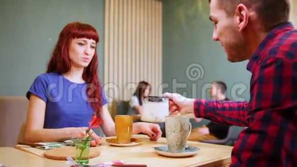 一对夫妇坐在一家咖啡馆的桌子旁一个人把饮料倒在杯子里视频的预览图