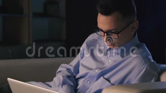一个男人坐在黑暗的办公室里的笔记本电脑前这个人工作到很晚视频的预览图