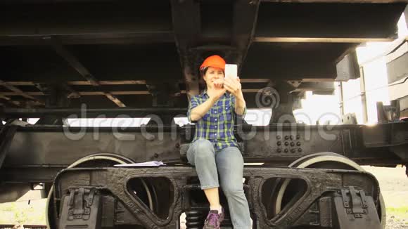 一名女铁路工人坐在一辆货车的运行齿轮的框架上视频的预览图
