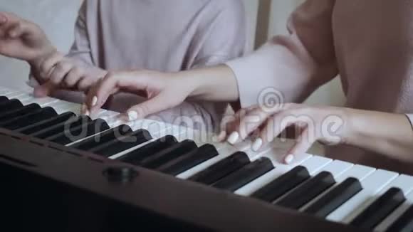 年轻的老师和小可爱的女孩在电动钢琴上演奏视频的预览图