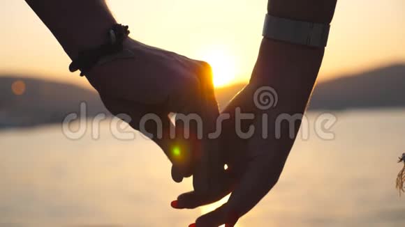 日落时分在大海的背景下男性和女性的手互相安慰和抚摸一对年轻夫妇视频的预览图