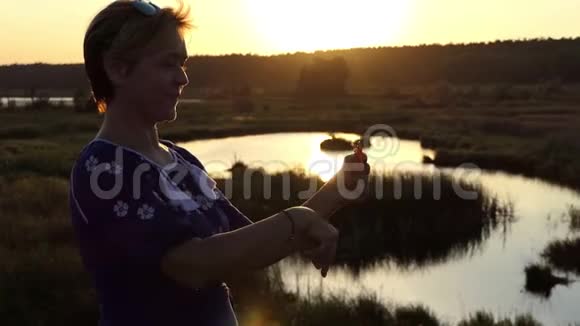 微笑的女人在夕阳西下的一个湖里辗转旋转者视频的预览图