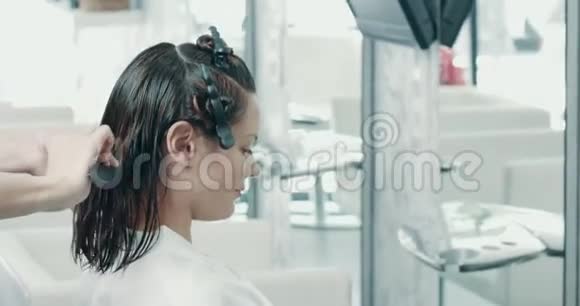 在沙龙剪发女人坐在椅子上理发师给她的头发准备理发视频的预览图