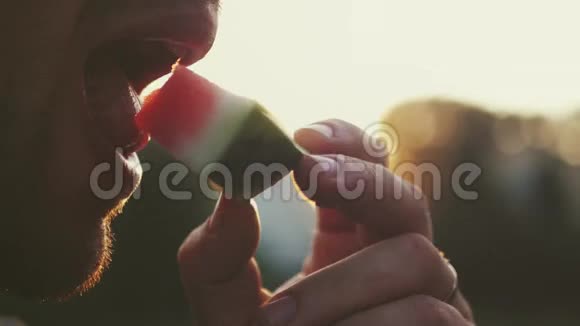 一个男人正在吃一个美味的红色成熟西瓜背景模糊4K3840x2160高清高清视频的预览图