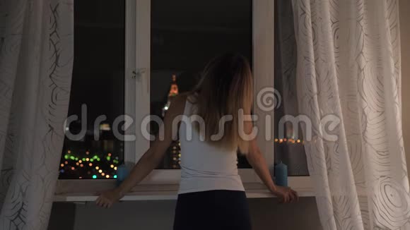 站在窗前的女人看着外面的夜晚和光明视频的预览图
