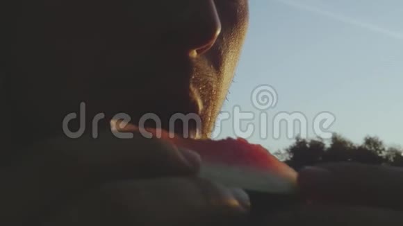 一个饥饿的人平息了他的食欲在外面的阳光下吃了一个美味的红色西瓜慢动作视频的预览图