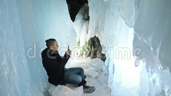 人类在一个冰洞里用智能手机交流围绕着神秘美丽的冰窟用户在社交中交流视频的预览图