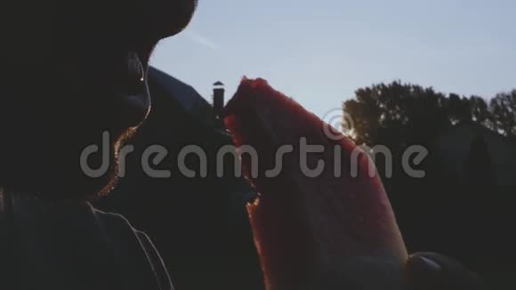 一个饥饿的人吃一个美味的红色成熟西瓜在夕阳的光线下在大自然特写镜头1920x1080视频的预览图