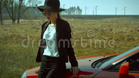 戴着墨镜和帽子的女士带着红色的车视频的预览图