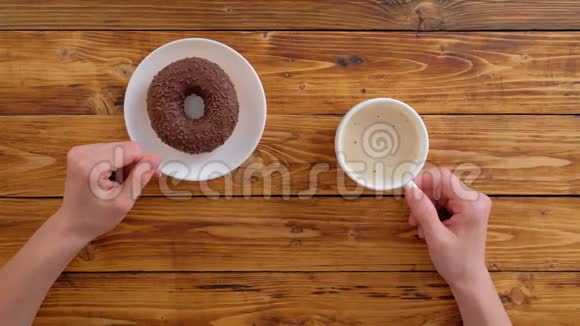 女人手里拿着咖啡和巧克力甜甜圈视频的预览图