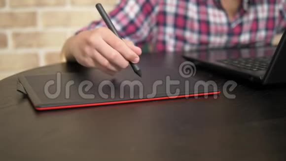 差不多了一个穿格子衬衫的少年用手写笔的手在图形平板电脑上工作视频的预览图