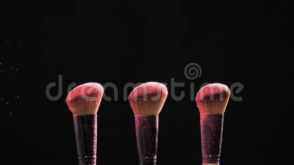 化妆品和美容的概念黑色背景上粉色粉末爆炸的化妆刷视频的预览图