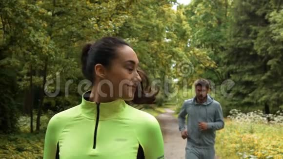 女跑步者在公园跑步和赢得比赛时会回头看他的搭档视频的预览图
