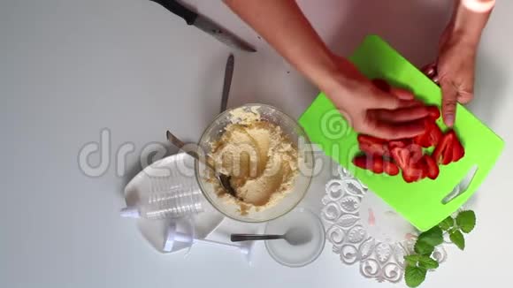 一个女人倒在一盘草莓上装饰馅饼附近是一个容器里的奶油视频的预览图