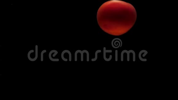 一只红番茄在黑色背景下掉在透明的水里视频的预览图