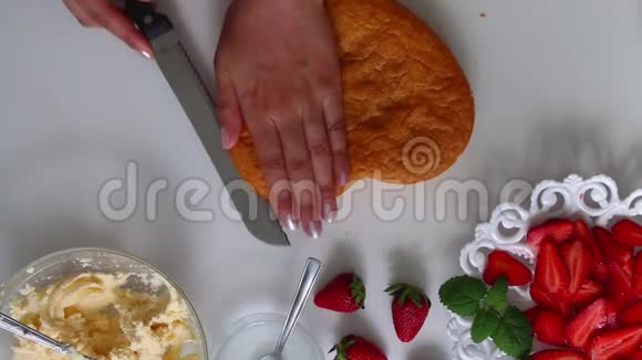 女人切饼干茶托旁边是一个草莓有一个奶油视频的预览图