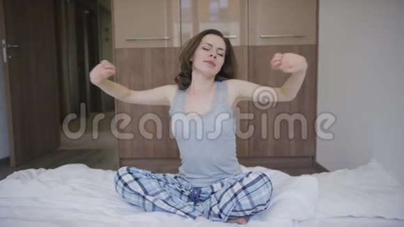 坐在床上伸展身体的漂亮女人视频的预览图