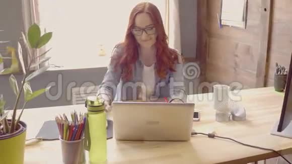 年轻女性自由职业者微笑和在电脑上工作的正面视图视频的预览图