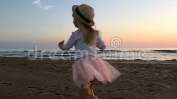 日落时一个小女孩沿着海滩奔跑视频的预览图