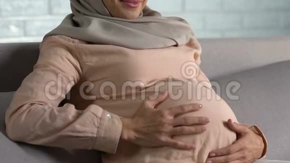 快乐的阿拉伯孕妇抚摸着肚子微笑着做母亲享受医疗保健视频的预览图