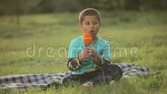 坐在公园里唱歌的男孩视频的预览图