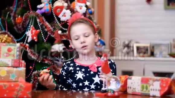 可爱漂亮的金发女孩她的头发上有一个粉红色的蝴蝶结穿着一件喜庆的漂亮连衣裙正在玩玩具圣诞鹿视频的预览图