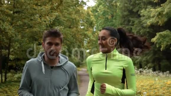 女孩和男人在晨跑中交流和微笑他们在公园里跑步视频的预览图