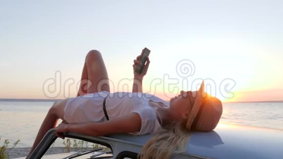手里拿着手机躺在车顶上视频的预览图