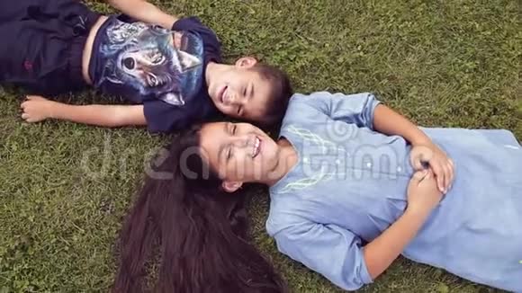 一个小男孩和一个女孩在草地上玩视频的预览图