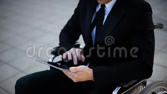 残疾人商人坐在室外轮椅用数字垫工作视频的预览图
